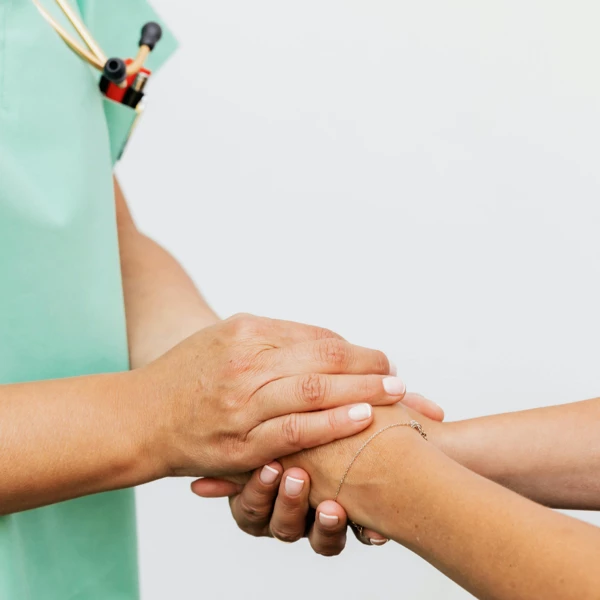 Pflegekraft hält die Hand eines Patienten bei der täglichen Visite zur Kontrolle der Genesung und des Wohlbefindens im Naghoi.