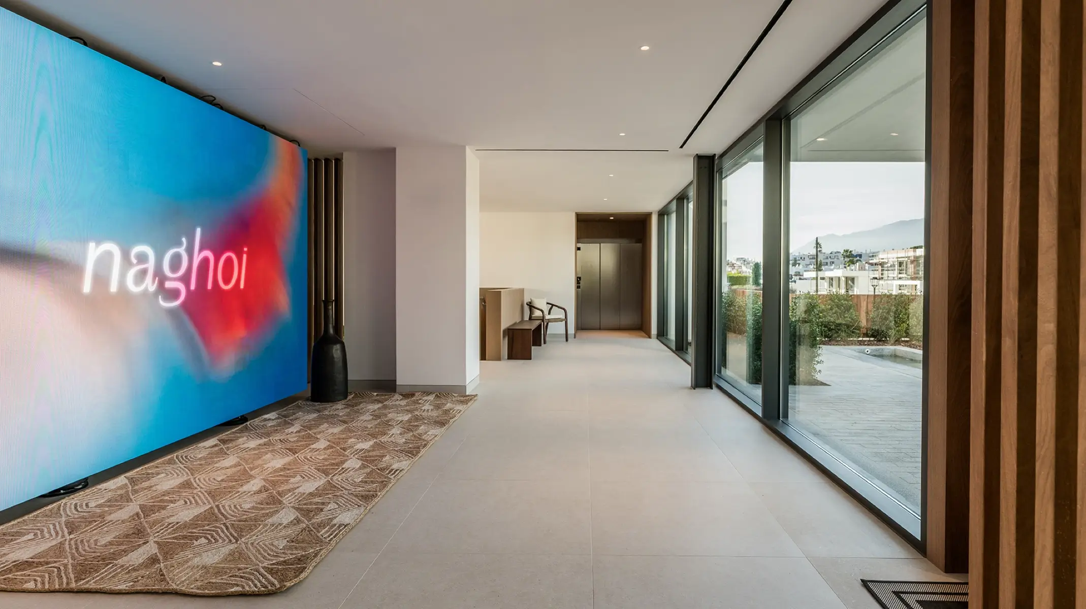 Eingangsbereich von Naghoi — modernes Interieur mit bodentiefen Fenstern mit Blick auf die Gärten im Facialteam Recovery Sanctuary in Marbella.